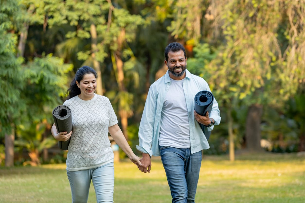 Joyful Morning Walk with Yoga Essentials in Nature,Happy Indian couple with yoga Essentials in Outdoor ground