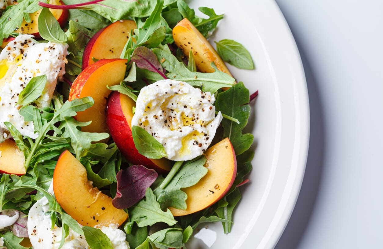 Burrata and peaches summer salad, white background.